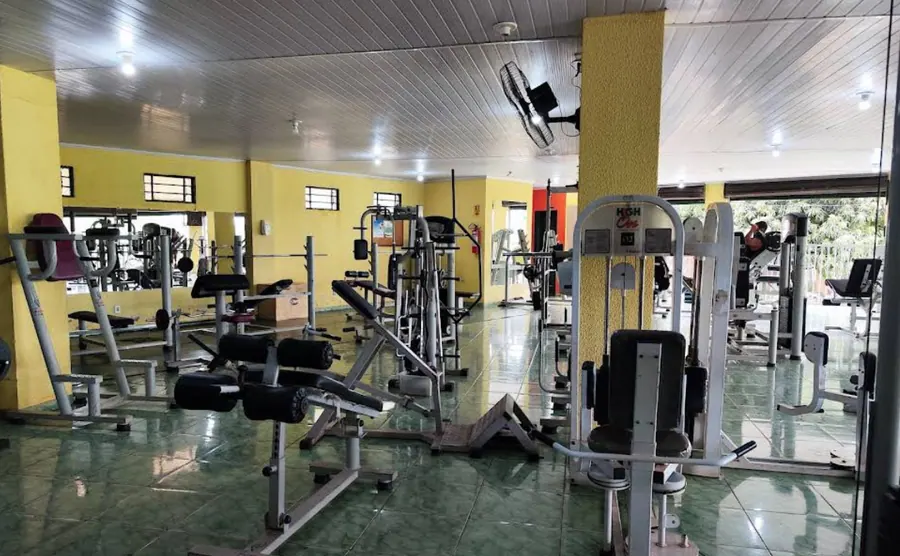 Salão de musculação com aparelhos e paredes amarelas